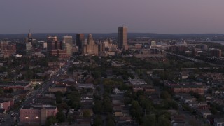 5.7K aerial stock footage of Seneca One Tower and skyline seen while descending past homes at twilight, Downtown Buffalo, New York Aerial Stock Footage | DX0002_204_037