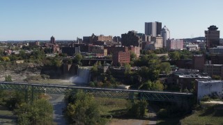 5.7K aerial stock footage of the city's skyline behind waterfalls on the river, Downtown Rochester, New York Aerial Stock Footage | DX0002_206_027