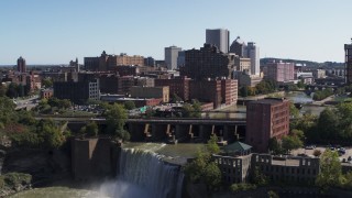 5.7K aerial stock footage approach the city's skyline behind waterfalls on the river, Downtown Rochester, New York Aerial Stock Footage | DX0002_206_028