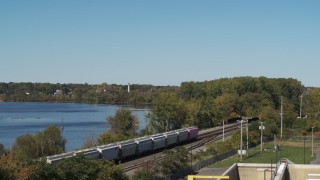 DX0002_211_041 - 5.7K aerial stock footage of descend by the lake to reveal tracks and a train in Syracuse, New York