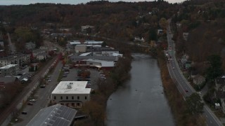 5.7K aerial stock footage of flying away from a grocery store by the river at sunset, Montpelier, Vermont Aerial Stock Footage | DX0002_220_038