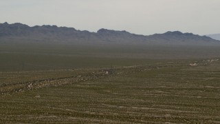 FG0001_000035 - 4K aerial stock footage of a bus traveling on a lonely Mojave Desert highway in Laughlin, Nevada, and zoom wider to reveal mountains