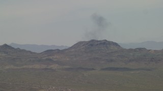 4K aerial stock footage of smoke rising from behind a Mojave Desert mountain in San Bernardino County, California Aerial Stock Footage | FG0001_000054