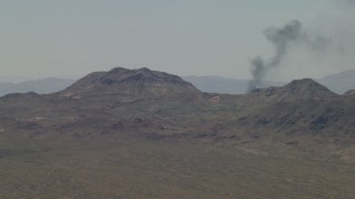 4K aerial stock footage of a smoke column behind Mojave Desert mountains in San Bernardino County, California Aerial Stock Footage | FG0001_000055