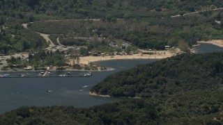 FG0001_000131 - 4K aerial stock footage of watercraft race past the marina near the beach on Silverwood Lake, California