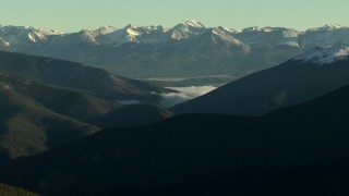 HDA13_438_02 - HD stock footage aerial video of fog between mountain slopes near snowy Rocky Mountains at sunrise, Colorado