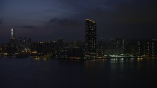 5K stock footage aerial video approach Kowloon skyscraper overlooking Victoria Harbor at night, Hong Kong, China Aerial Stock Footage | SS01_0157