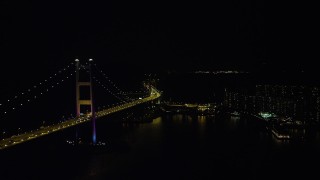 5K stock footage aerial video of flying between the Tsing Ma Bridge and waterfront apartment buildings at night in Hong Kong, China Aerial Stock Footage | SS01_0245