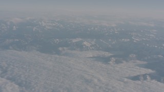 WA002_033 - 4K stock footage aerial video pan across a blanket of clouds and snowy Sierra Nevada Mountains, California