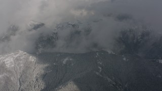 4K stock footage aerial video of a bird's eye view of clouds, revealing snowy mountain ridges in Washington Aerial Stock Footage | WA004_080