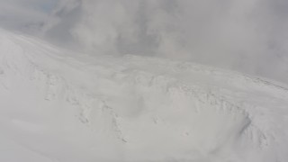 4K stock footage aerial video pan across a snowy peak and clouds to a view of wilderness in Washington Aerial Stock Footage | WA004_085