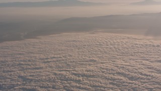 WA005_012 - 4K stock footage aerial video approach mountains at sunset, and tilt to clouds below in Southern California