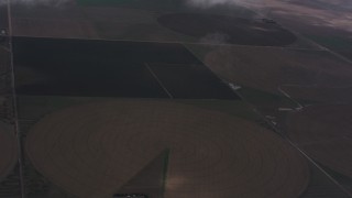 WA005_027 - 4K stock footage aerial video fly through clouds to reveal farms and circular crop fields in Kansas