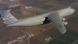 4K stock footage aerial video of a Lockheed C-5 in flight over farms and leaving frame in Northern California Aerial Stock Footage | WAAF01_C081_0117PS