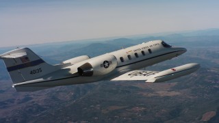 4K stock footage aerial video pan to reveal a Learjet C-21 flying over hills in Northern California Aerial Stock Footage | WAAF02_C005_0117F9