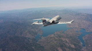 4K stock footage aerial video of revealing a Learjet C-21 flying toward hills and a lake in Northern California Aerial Stock Footage | WAAF02_C007_0117AS