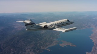 4K stock footage aerial video reveal a Learjet C-21 flying over hills toward a lake in Northern California Aerial Stock Footage | WAAF02_C008_0117ED