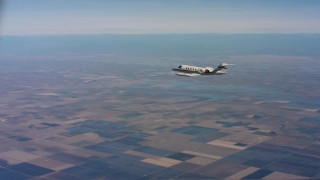 4K stock footage aerial video of tracking a Learjet C-21 over farmland and leaving frame in Northern California Aerial Stock Footage | WAAF02_C012_01179Q