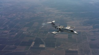 4K stock footage aerial video of a Learjet C-21 as it turns and flies over farmland in Northern California Aerial Stock Footage | WAAF02_C014_0117MN