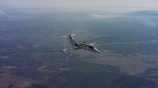 4K stock footage aerial video of flying around a Learjet C-21 in the air over farmland of Northern California Aerial Stock Footage | WAAF02_C015_01179B