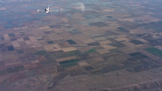 4K stock footage aerial video of a reverse view of a Learjet C-21 over farmland in Northern California Aerial Stock Footage | WAAF02_C016_0117AV