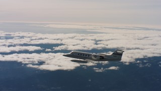 4K stock footage aerial video of a Learjet C-21 in flight near cloud-topped mountains in Northern California Aerial Stock Footage | WAAF02_C022_01171S