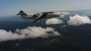 4K stock footage aerial video of a Learjet C-21 flying over patchy clouds toward ocean in Northern California Aerial Stock Footage | WAAF02_C030_01172A