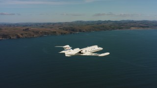 4K stock footage aerial video track a Learjet C-21 flying over the ocean near the coast in Northern California Aerial Stock Footage | WAAF02_C036_0117TJ