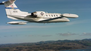 WAAF02_C037_011796 - 4K stock footage aerial video of following a Learjet C-21 flying along the coast in Northern California