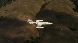 4K stock footage aerial video of panning across hills to reveal a Learjet C-21 in flight in Northern California Aerial Stock Footage | WAAF02_C045_011782