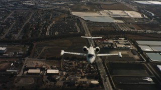 4K stock footage aerial video of a reverse view of a Learjet C-21 flying over industrial buildings in Northern California Aerial Stock Footage | WAAF02_C055_01177K