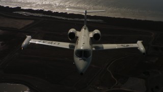 4K stock footage aerial video of a reverse view of a Learjet C-21 entering frame and flying over bay, Northern California Aerial Stock Footage | WAAF02_C059_01174D