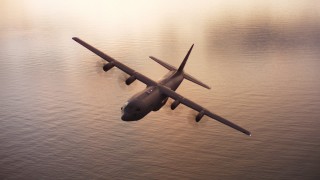 WAAF06_C086_011941 - 4K stock footage aerial video of a Lockheed Martin C-130J over San Francisco Bay at sunset, California